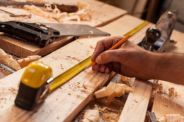 carpenter taking measurement of a wooden plank